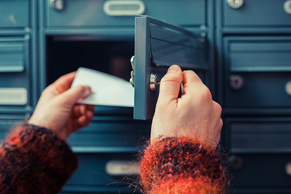 Close-up of a person's hands taking a letter out of a PO box.