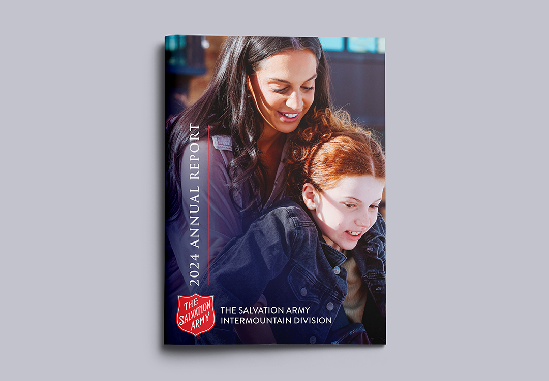 Report design cover example featuring a full-bleed photo of an adult woman hugging a girl from behind with the words "2024 Annual Report - the Salvation Army Intermountain Division."