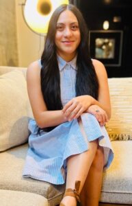 Latinx Therapist Project Executive Director Bridget Sanchez - a young woman with long brown hair sitting on a white couch smiling at the camera.